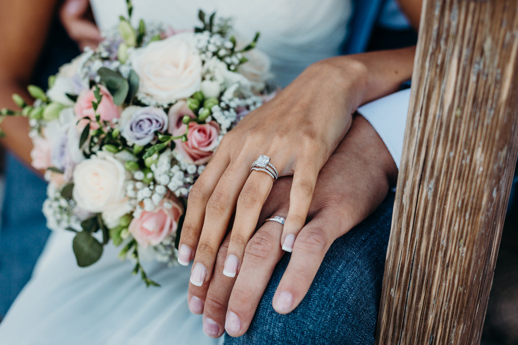 Newly wed couple holding hands displaying rings