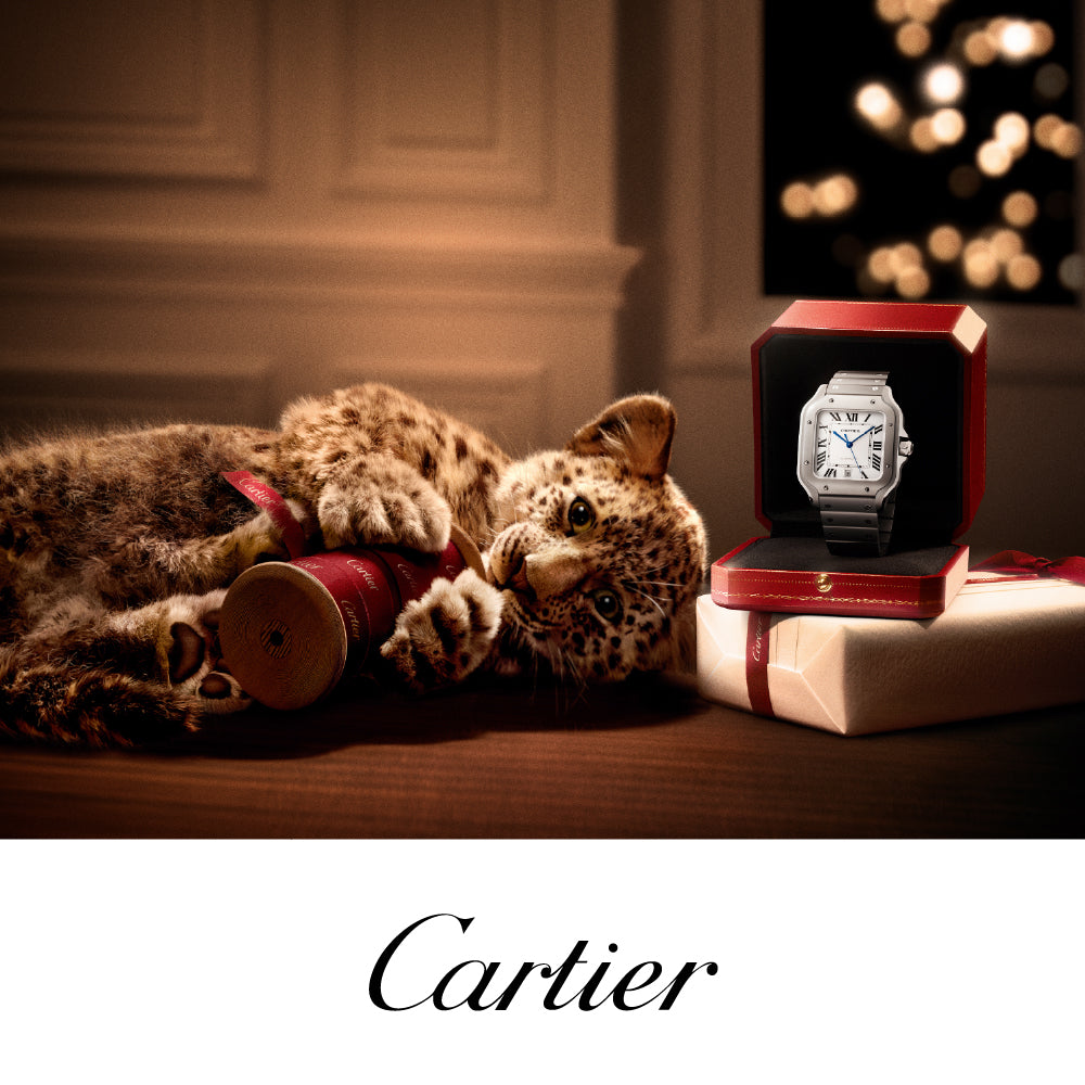 Cartier watch in a red box with a leopard plush toy on a wooden surface.