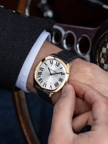 Man adjusting his Cartier watch in car. 