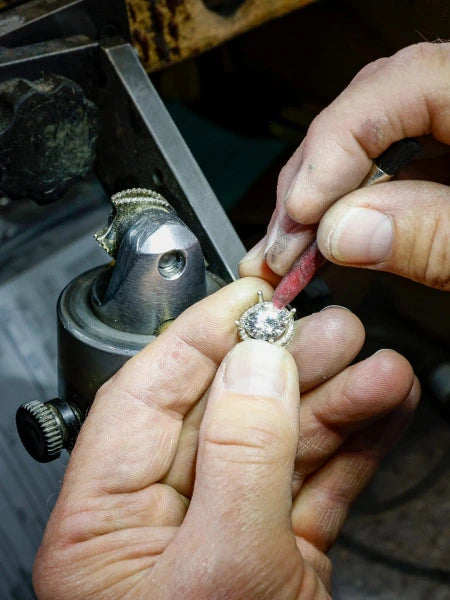 A person setting a diamond into a ring halo. 